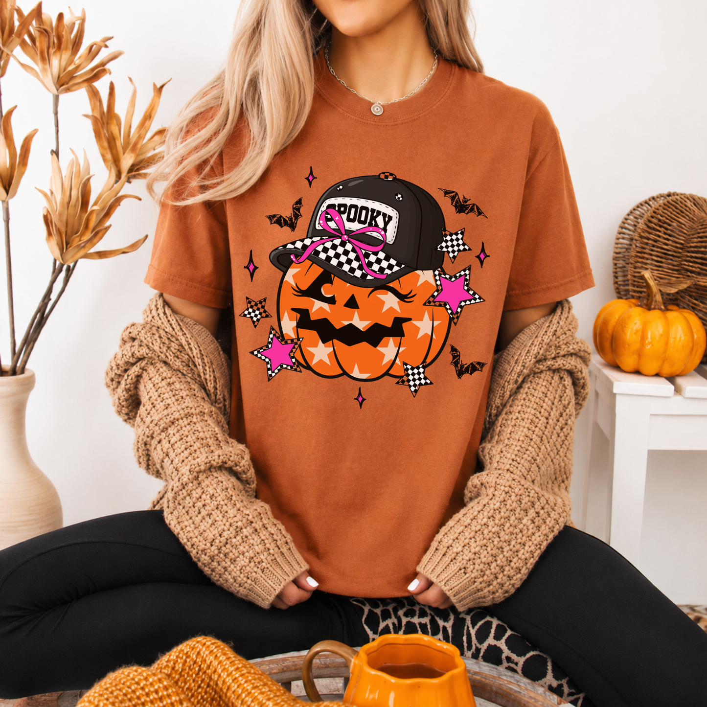 Person wearing a Halloween-themed orange t-shirt with a pumpkin design, sitting in a cozy indoor setting.